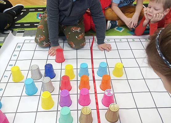 Dzieci kodują na macie z wykorzystaniem kolorowych kubków