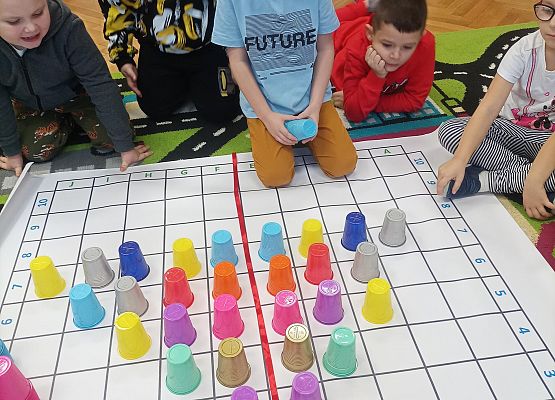 Dzieci kodują na macie z wykorzystaniem kolorowych kubków