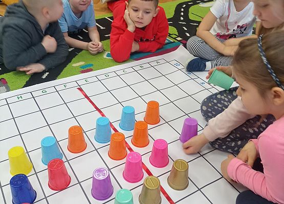 Dzieci kodują na macie z wykorzystaniem kolorowych kubków