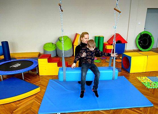 Uczeń z nauczycielką podczas ćwiczeń na podwieszanym wałku