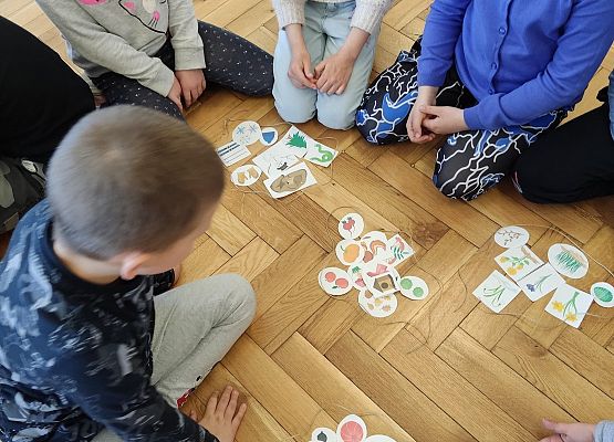 Uczniowie siedzą na podłodze i układają karty tworząc zbiory