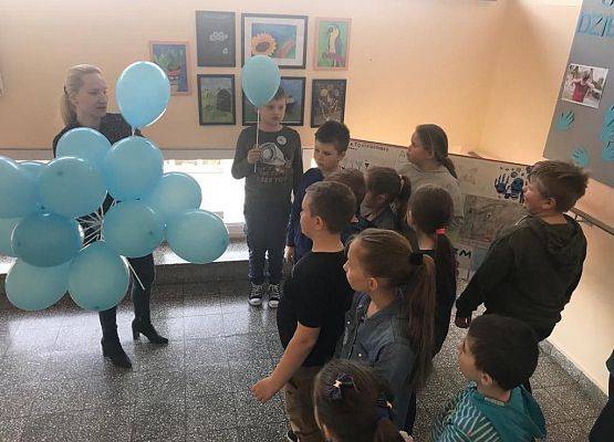 Nauczycielka rozdaje uczniom niebieskie balony