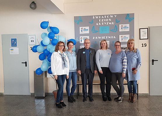 Dyrektor z pracownikami szkoły, wszyscy w niebieskich strojach