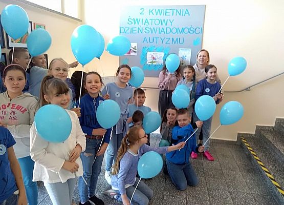 Uczniowie trzymają w dłoniach niebieskie balony