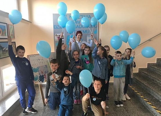 Uczniowie niosą niebieskie balony