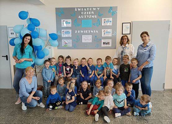 Zdjęcie grupowe przedszkolaków, nauczycielek i opiekunek. Wszyscy ubrani na niebiesko.