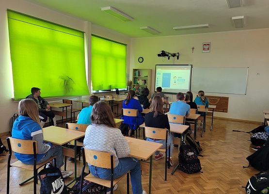 Uczniowie siedzą w ławkach i oglądają film