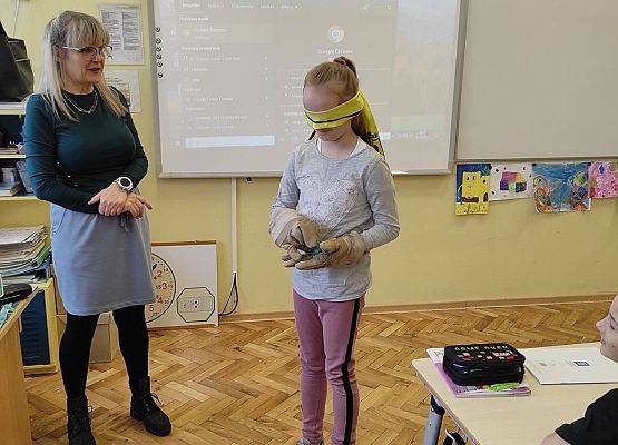 Uczennica z zawiązaną opaską na oczach trzyma przedmiot