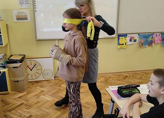 Nauczycielka zakłada uczennicy opaskę na oczy