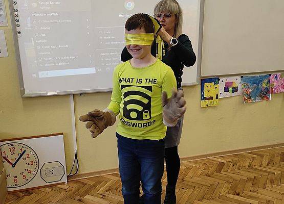 Nauczycielka zakłada uczniowi opaskę na oczy