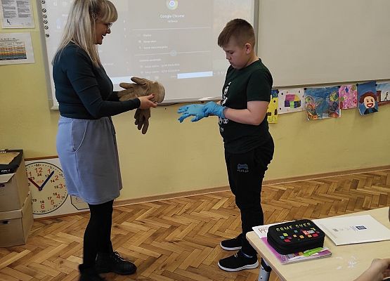 Nauczycielka podaje rękawice uczniowi