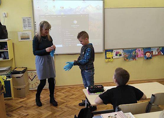 Nauczycielka podaje rękawice uczniowi