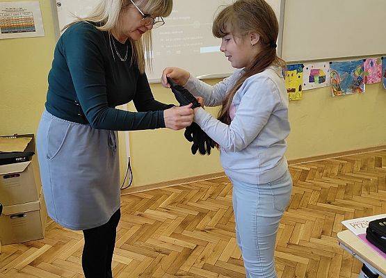 Nauczycielka podaje dziewczynce gumowe rękawiczki