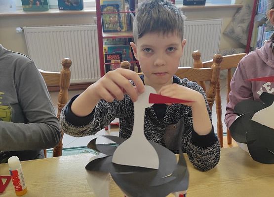 Uczeń prezentuje papierowego bociana