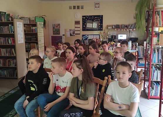 Uczniowie siedzą w bibliotece i oglądają prezentację multimedialną