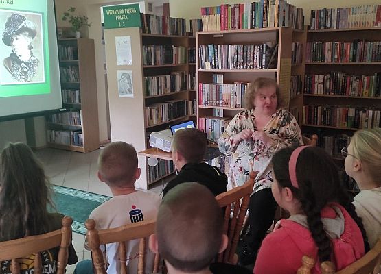 Uczniowie siedzą w bibliotece i oglądają prezentację multimedialną