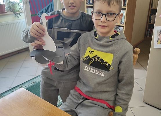 Uczniowie prezentują papierowego bociana