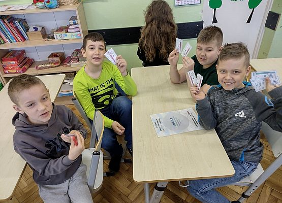 Chłopcy siedzą przy stoliku i liczą zabawkowe pieniążki