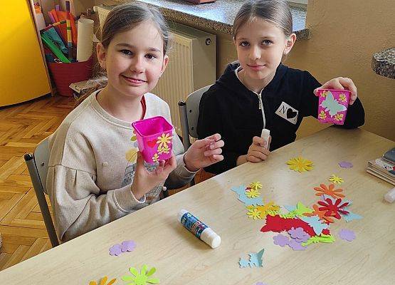 Uczniowie ozdabiają doniczki kolorowymi kwiatami z papieru