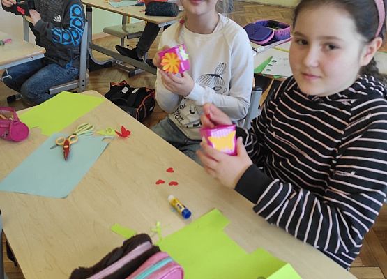Uczniowie ozdabiają doniczki kolorowymi kwiatami z papieru