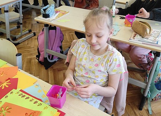 Uczniowie ozdabiają doniczki kolorowymi kwiatami z papieru