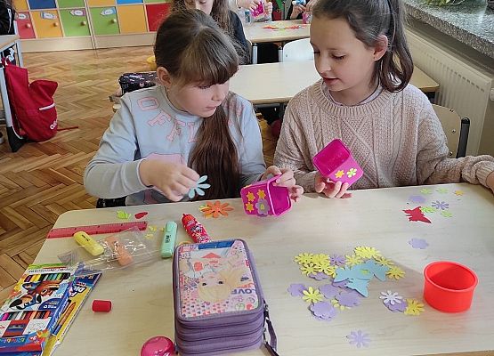 Uczniowie ozdabiają doniczki kolorowymi kwiatami z papieru