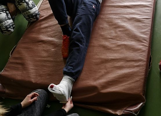 Statysta leży na materacu podczas zadań z pierwszej pomocy