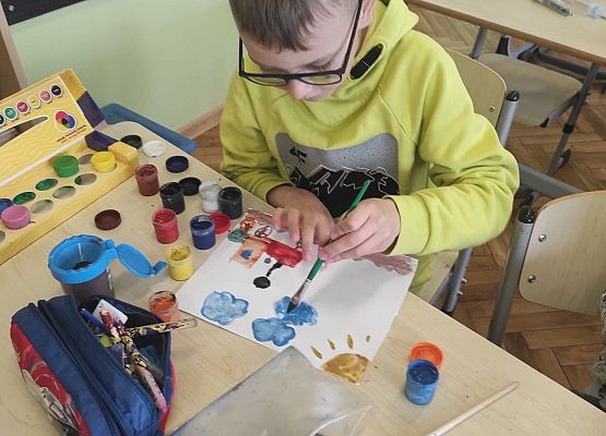 Uczeń maluje farbkami