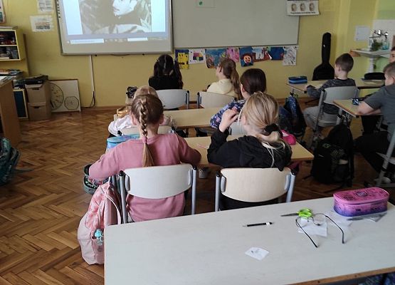 Uczniowie siedzą w ławkach i oglądają prezentację