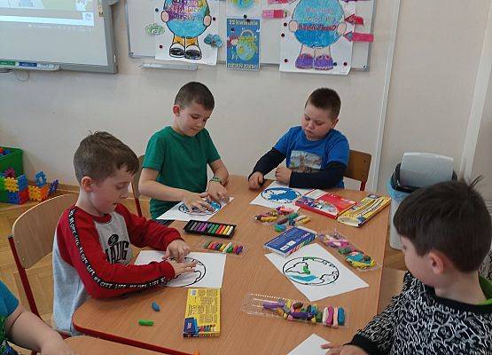 Dzieci wyklejają plasteliną rysunek planety Ziemia