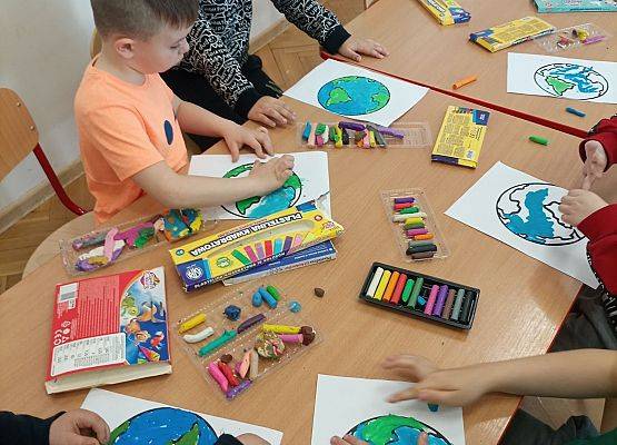 Dzieci wyklejają plasteliną rysunek planety Ziemia