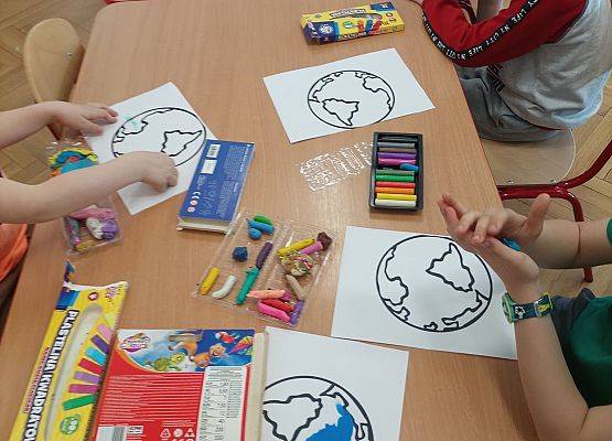 Dzieci wyklejają plasteliną rysunek planety Ziemia