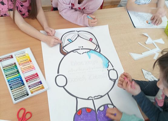 Dziecy wykonują wspólną pracę plastyczną pastelami