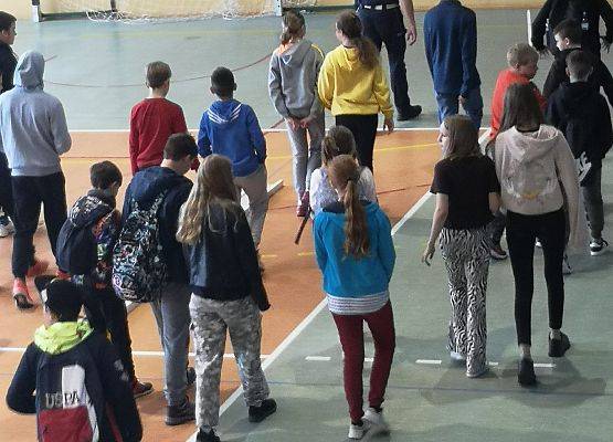 Uczniowie stoją w sali gimnastycznej