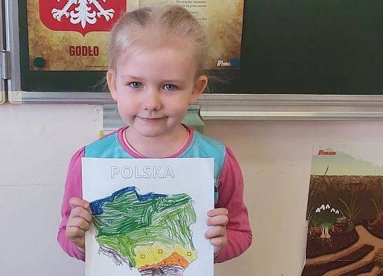 Dziewczynka prezentuje pokolorowany kontur Polski