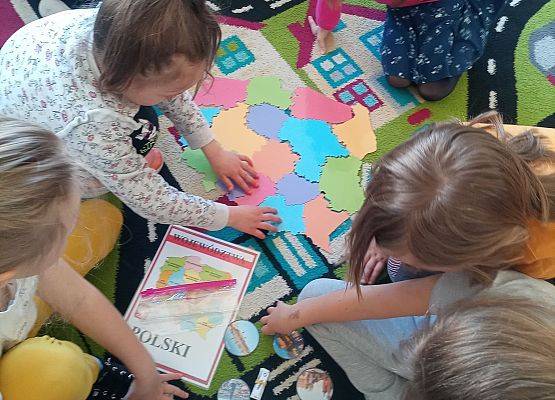 Dzieci siedzą na dywanie i układają puzzle