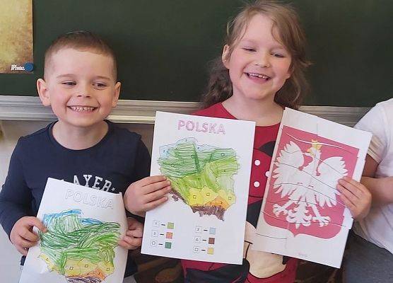 Dzieci prezentuję godło i mapy Polski