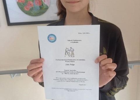 Nagrodzona uczennica prezentuje dyplom