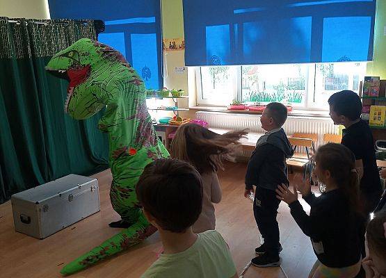 Dzieci tańczą z dinozaurem