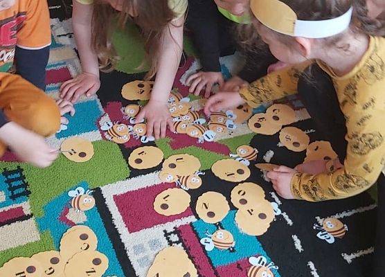 Dzieci siedzą na dywanie i układają karty
