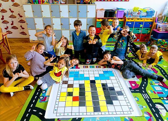 Dzieci siedzą na dywanie przy zakodowanym obrazku