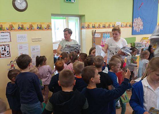 Kobieta rozdaje przedszkolakom koszulki