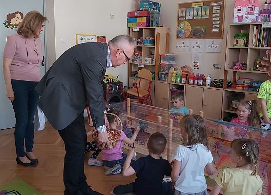 Pan dyrektor i pani dyrektor rozdają  cukierki dzieciom