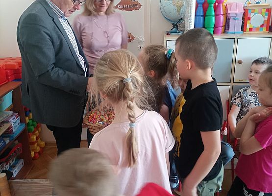 Pan dyrektor i pani dyrektor rozdają  cukierki dzieciom