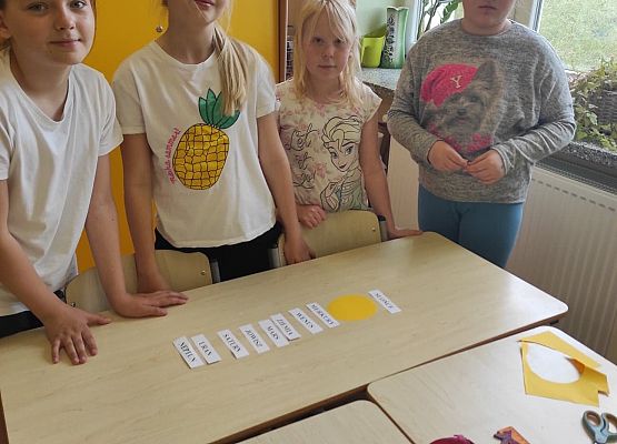 Uczennice stoją przy ławce i prezentuj wykonane zadanie