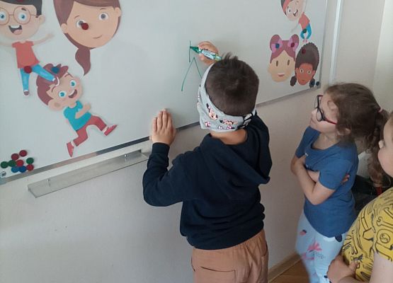 Chłopiec z zasłoniętymi oczami rysuje po tablicy