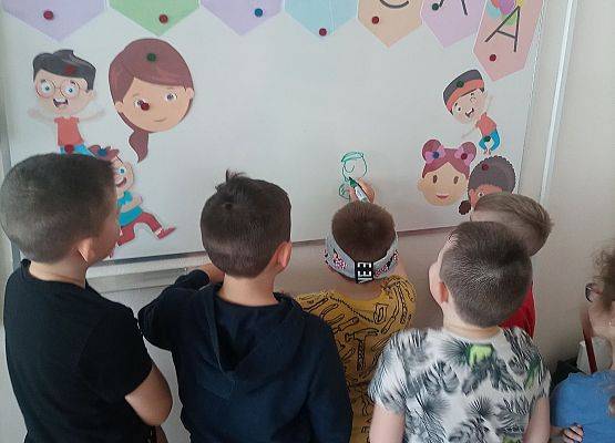 Chłopiec z zasłoniętymi oczami rysuje po tablicy