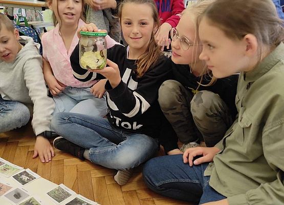 Uczennica pokazuje ślimaka w słoiku