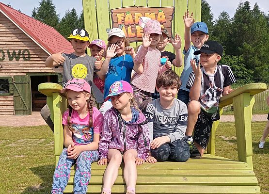 Dzieci siedzą na wielkim drewnianym krześle