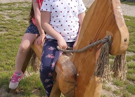 Dwie dziewczynki siedzą na drewnianym koniku